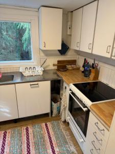 uma pequena cozinha com armários brancos e uma janela em Mysig stuga i Nävesta em Örebro