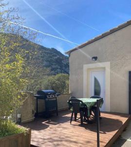 um pátio com uma mesa, cadeiras e comodidades para churrascos em Le St Benoit em Saint-Guilhem-le-Désert