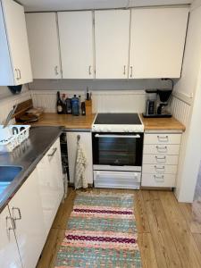 uma cozinha com armários brancos e um tapete no chão em Mysig stuga i Nävesta em Örebro