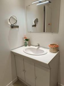 uma casa de banho com um lavatório branco e um espelho. em Le St Benoit em Saint-Guilhem-le-Désert