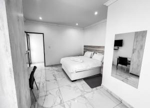 1 dormitorio con cama, mesa y espejo en Onamungundo Backpackers, en Walvis Bay