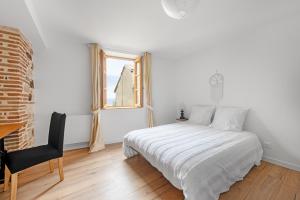 ein weißes Schlafzimmer mit einem Bett und einem Fenster in der Unterkunft Le Duplex du Castel haut - Escapade Tarnaise in Castelnau-de-Montmiral