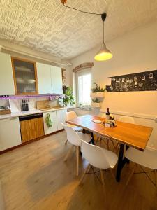 - une cuisine avec une table en bois et des chaises blanches dans l'établissement Sweet Apartment for Friends and Family in Valpolicella, à San Pietro in Cariano