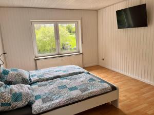 1 dormitorio con cama y ventana en Alte Mühle - Ferienwohnung Tamara, en Herdwangen-Schönach