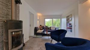 a living room with a fireplace and blue chairs at Maison calme avec Spa et beau paysage, à 40mn des plages in Saint-Jean-de-Livet
