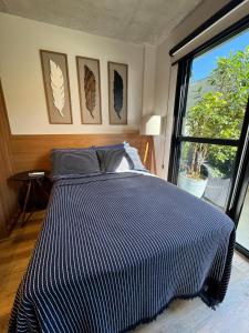een slaapkamer met een bed met een blauw en wit gestreept dekbed bij Studio Garden in Curitiba