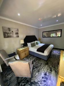 a bedroom with a bed and two chairs in it at Waterfront Guest House in Hartbeespoort