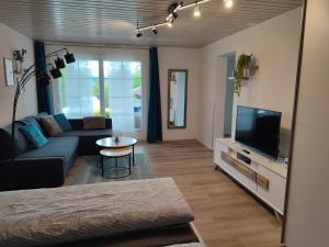 ein Wohnzimmer mit einem Sofa und einem TV in der Unterkunft Kleine Auszeit - 2-Zimmer Ferienwohnung in Spiez