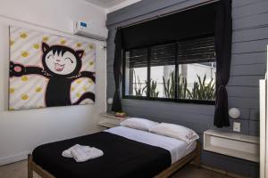 a bedroom with a bed with a cat painting on the wall at Aldea Hostel in Córdoba