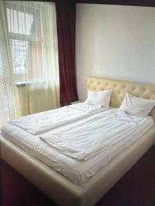 uma cama grande com lençóis brancos e uma janela em Casa Verde Poiana Brasov em Poiana Brasov