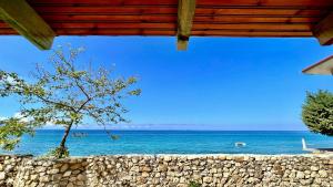a view of the ocean from a beach with a stone wall at Villa Kate in Borsh