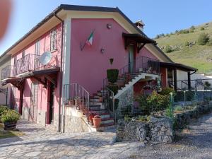 Una casa rosa con escaleras en el costado. en Agriturismo Casa Della Nonna, en Mormanno