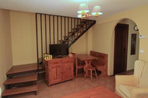 sala de estar con TV, mesa y escalera en La Casita Amarilla, en Los Molinos