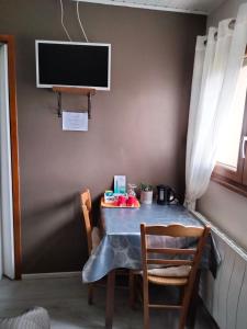 mesa con sillas y TV en la pared en Chambres d'Hôtes Arnold en Dambach-la-Ville