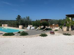 un patio trasero con piscina, mesa y sillas en Trulli Santa Maria Odegitria Relais, en Ostuni