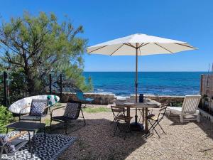 a table and chairs with an umbrella and the ocean at Le Cabanon, pieds dans l'eau, vue exceptionnelle in Fréjus