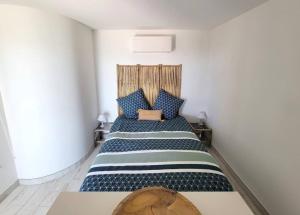 a bedroom with a bed with blue and white pillows at Le Cabanon, pieds dans l'eau, vue exceptionnelle in Fréjus