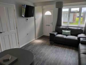 a living room with a couch and a table at California Sands - 2 x Modern Two Double Bedroom Chalets - short stroll to the beach - nr Great Yarmouth & Norfolk Broads in Scratby
