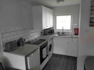a kitchen with white cabinets and a sink and a dishwasher at California Sands - 2 x Modern Two Double Bedroom Chalets - short stroll to the beach - nr Great Yarmouth & Norfolk Broads in Scratby +7 photos