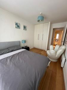 a bedroom with a bed and a white chair at The Fitz Apartment in Dublin