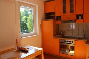 cocina con armarios naranjas, mesa y ventana en PARK Apartment en Bijeljina
