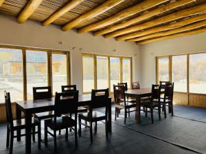 a dining room with tables and chairs and windows at HUNDER TAMARIX RESORT in Leh