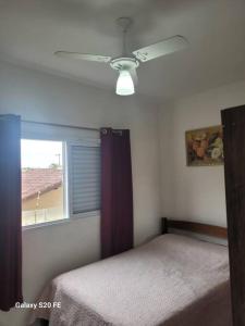 a bedroom with a ceiling fan and a window at Apartamento prox Sesc Bertioga in Bertioga
