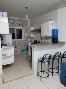 a kitchen with three chairs at a counter in a kitchen at Apartamento prox Sesc Bertioga in Bertioga