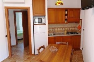 a kitchen with a wooden table and a white refrigerator at Bari Sardo Le More Suite 4 in Bari Sardo