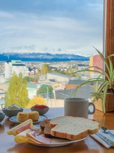 einen Tisch mit einem Teller Brot und einer Tasse Kaffee in der Unterkunft Hostería Aonikenk in Ushuaia