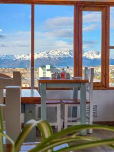 a table and chairs on a balcony with a view of mountains at Hostería Aonikenk in Ushuaia