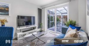 a living room with a blue couch and a tv at Modern 2 Bed Apartment on Edge of City Centre, 2xFREE Private Parking, Ground Floor & Private Entrance in Quiet Neighbourhood in Peterborough