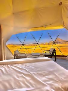a room with two chairs and a bed in a tent at Rum Green Camp in Wadi Rum