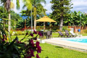 a patio with a table and umbrella next to a pool at Hotel campestre La Floresta in Armenia