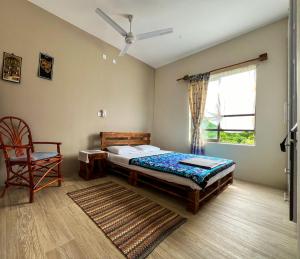 ein Schlafzimmer mit einem Bett, einem Stuhl und einem Fenster in der Unterkunft Vipingo Palm Ridge Apartment - 406 in Mombasa