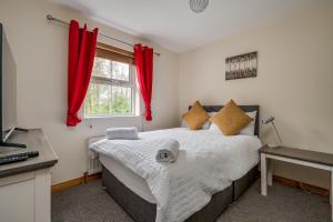 a bedroom with a bed with red curtains and a desk at Stylish & spacious 3 bedroom entire house in Lisburn with parking in Lisburn