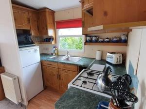 a kitchen with a stove and a white refrigerator at Bay View Hawkins Battery Holiday park in Kingsand