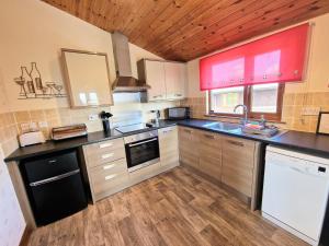 a large kitchen with wooden cabinets and a counter top at Cleish 7 With Private Hot Tub - Fife - Loch Leven - Lomond Hills - Pet Friendly in Kelty