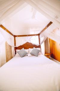 a bedroom with a white bed with two pillows at JAMAKI Hospitality in Mombasa