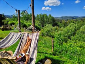 two people laying in a hammock in a field at Czarna Owca in Istebna +163 photos