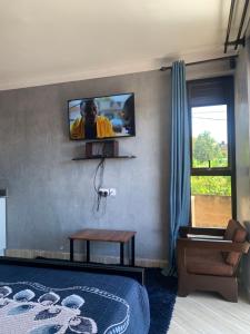 a bedroom with a tv on the wall and a bed at xfurnishedapartments in Kampala