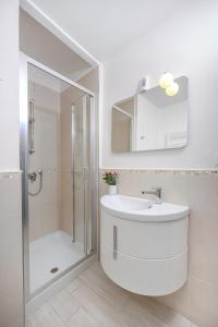 a white bathroom with a sink and a shower at La Piazzetta in centro in La Spezia