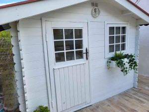 einen weißen Schuppen mit einer Tür und einem Fenster in der Unterkunft villa bambou in Saleilles