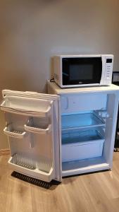 einen offenen Kühlschrank mit einer Mikrowelle darüber in der Unterkunft Glomma House in Kongsvinger