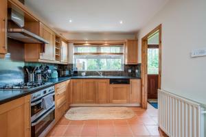 a kitchen with wooden cabinets and a sink at Stylish & spacious 3 bedroom entire house in Lisburn with parking in Lisburn