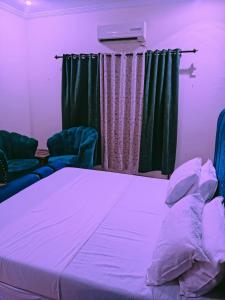 Ce lit se trouve dans un dortoir doté de 2 chaises et d'une lumière violette. dans l'établissement Home Inn Guesthouse, à Islamabad