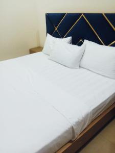 - un lit avec des draps et des oreillers blancs dans l'établissement Home Inn Guesthouse, à Islamabad