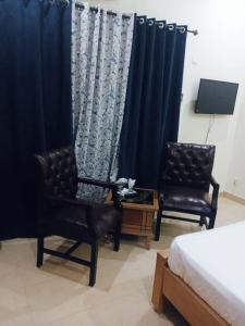 - une chambre avec deux chaises, un lit et des rideaux dans l'établissement Home Inn Guesthouse, à Islamabad