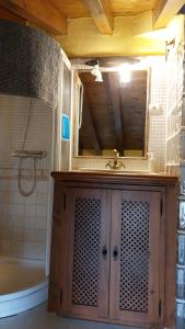 een badkamer met een wastafel, een spiegel en een bad bij El Tinao de la Hiruela (Entremelojos) in La Hiruela