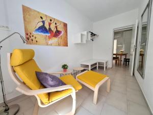 a living room with yellow chairs and a painting on the wall at Apartment Sandy in Hvar